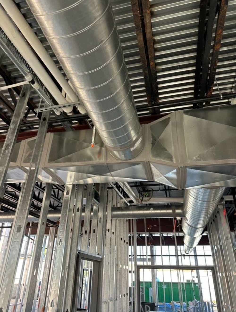 Spiral duct running along a rectangular trunk line in a commercial build-out